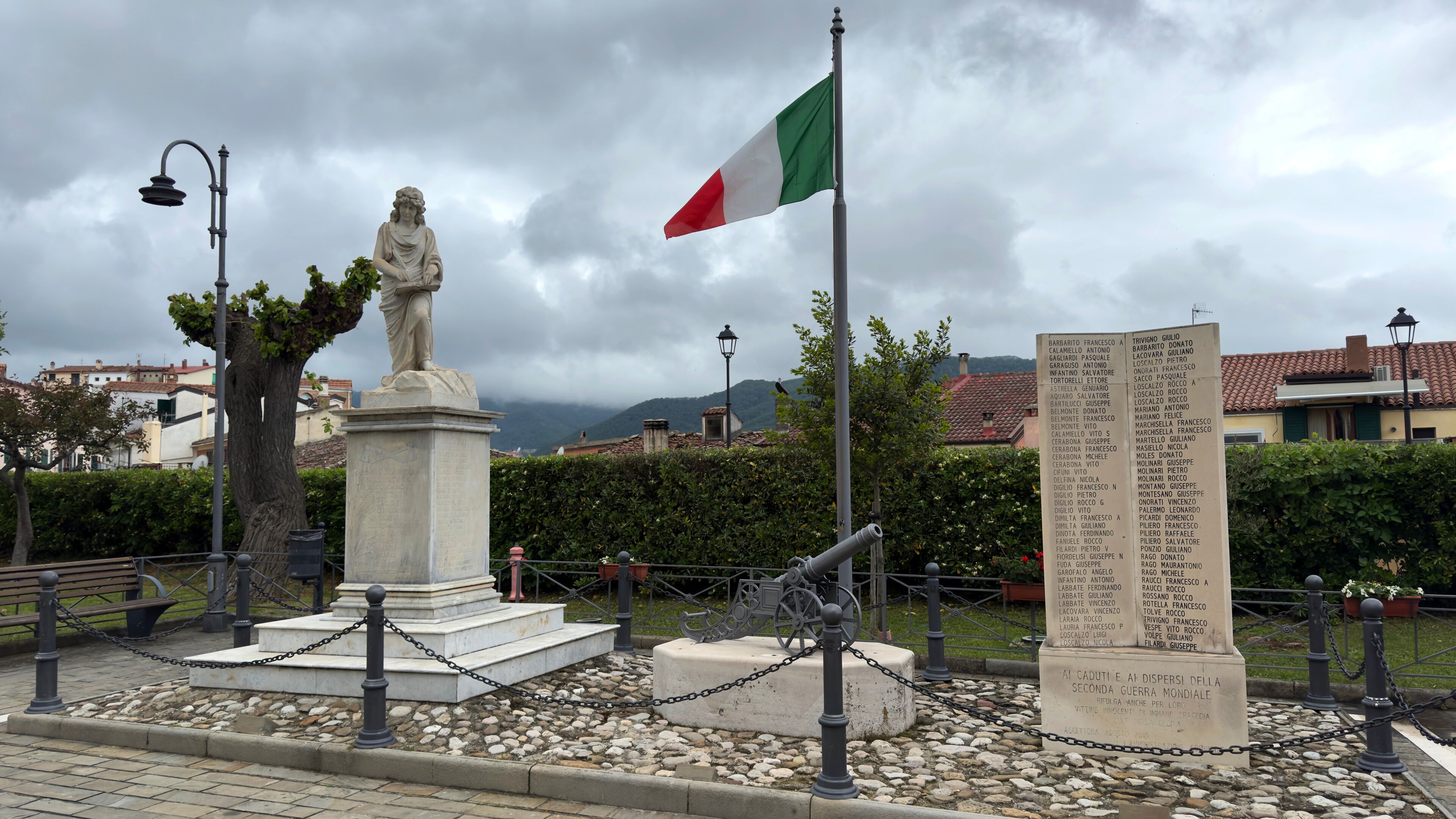 A statue, a flag, and a monument with inscriptions.
