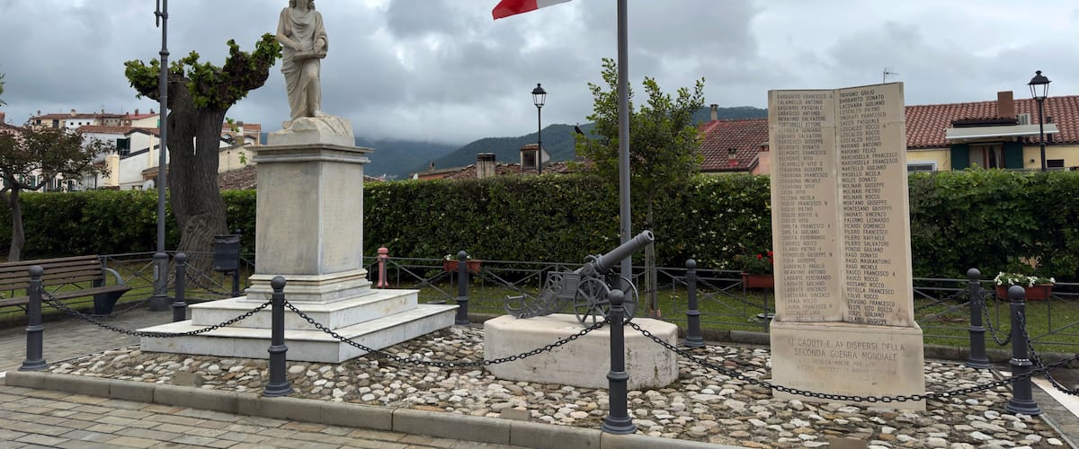 A statue, a flag, and a monument with inscriptions.