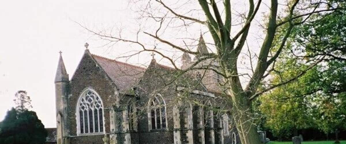 A church with a large lawn and a bench in front.