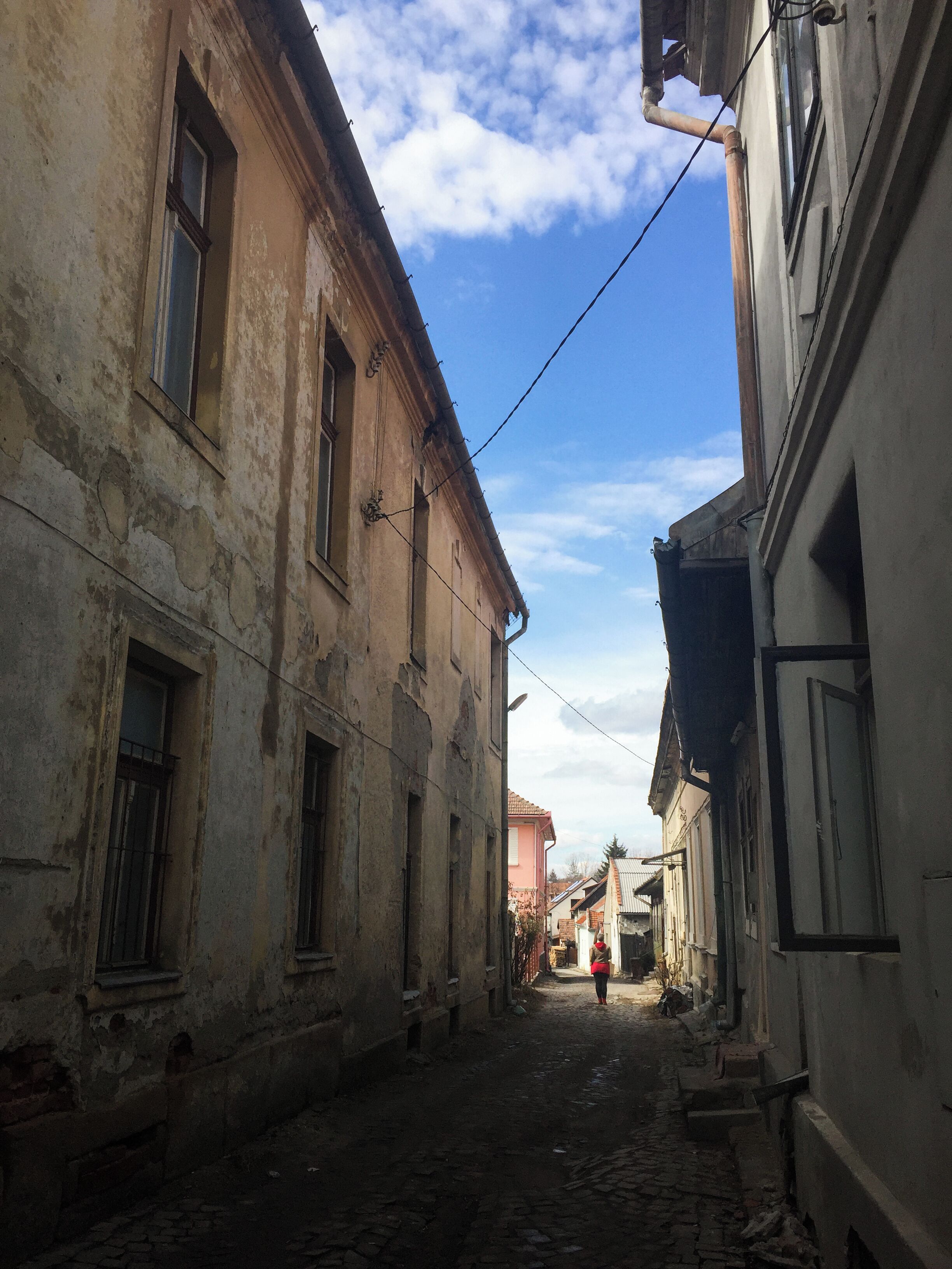 A narrow cobblestone street flanked by old buildings with visible wear and tear.