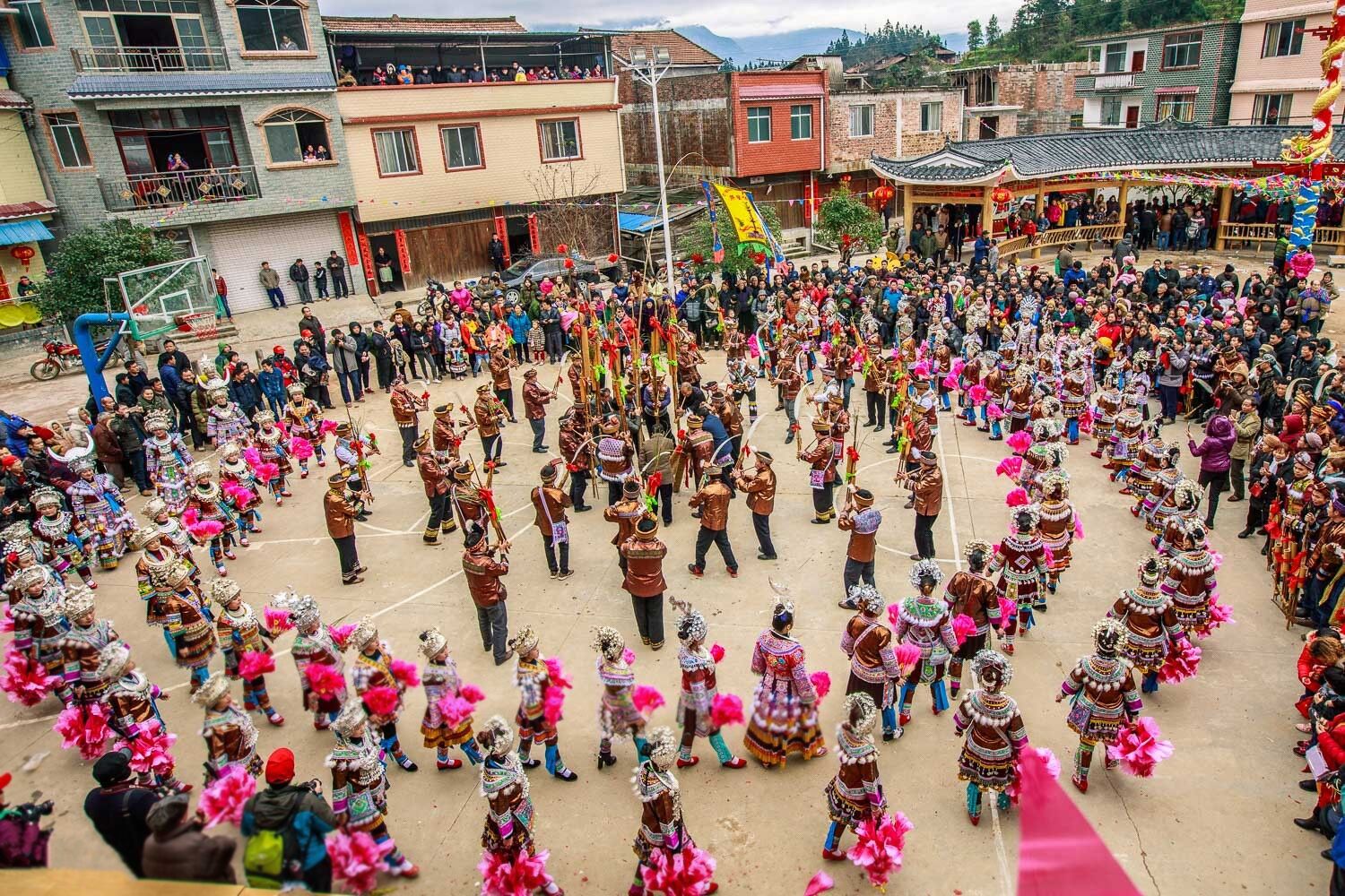 A traditional dance performance in a village setting with spectators.