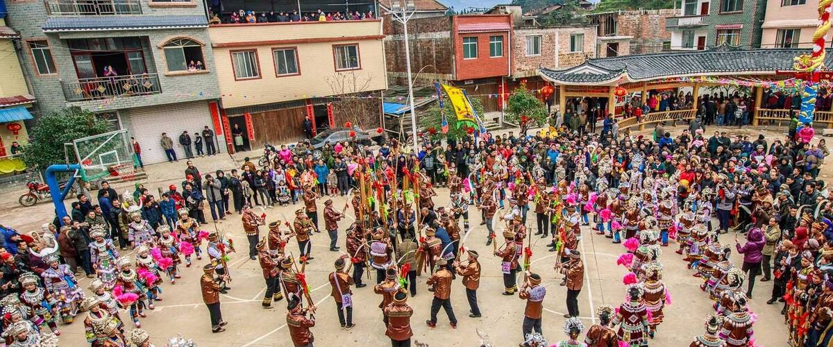 A traditional dance performance in a village setting with spectators.