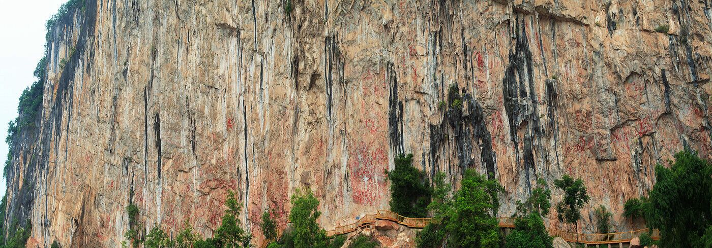 A large rock face with vertical striations and sparse vegetation at the base.
