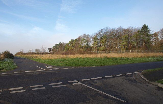 A rural road with a pedestrian crossing and a traffic island.