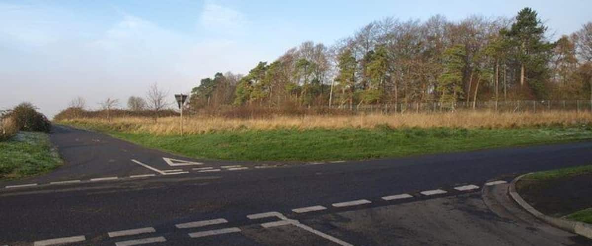 A rural road with a pedestrian crossing and a traffic island.