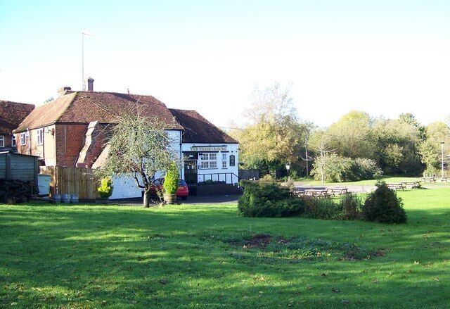 A grassy field with a white building and a red car.