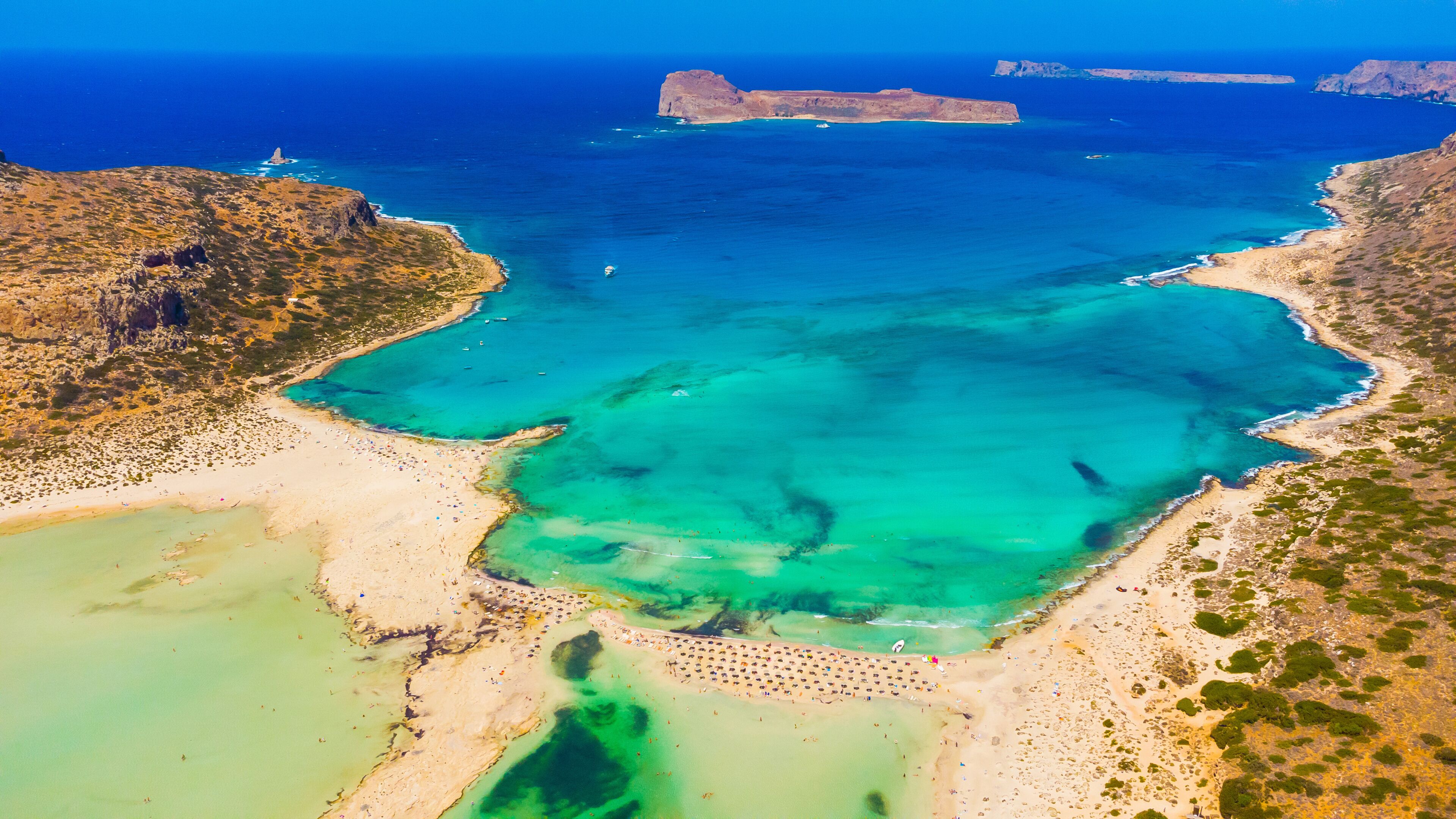 A coastal landscape with clear turquoise waters, sandy beaches, and rocky cliffs.