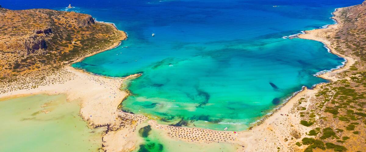 A coastal landscape with clear turquoise waters, sandy beaches, and rocky cliffs.