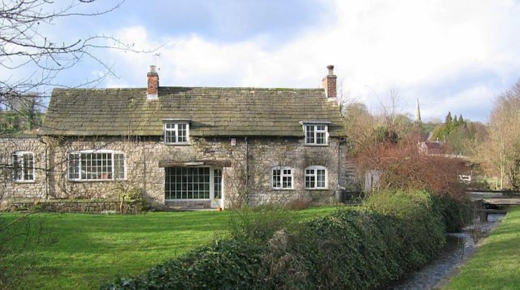 Brookside Cottage, Fenny Bentley Bentley Brook runs parallel to the Buxton-Ashbourne Road. Stone footbridges span the gap between the road and the houses. The spire of the Church of St Edmund can just be seen.