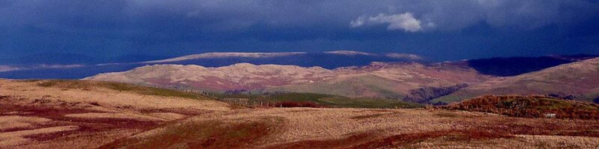 Dramatic skies over the Lune Valley, 3 km from Old Town, Cumbria, Great Britain. Strong north-westerly winds were chasing sunlight and shadow over the fells east of the Lune. The long ridge of Holme Knott is in sunlight as is the very top edge of Baugh Fell above it.