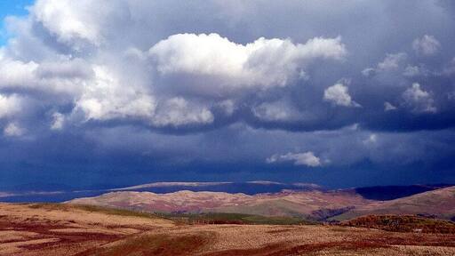 Dramatic skies over the Lune Valley, 3 km from Old Town, Cumbria, Great Britain. Strong north-westerly winds were chasing sunlight and shadow over the fells east of the Lune. The long ridge of Holme Knott is in sunlight as is the very top edge of Baugh Fell above it.