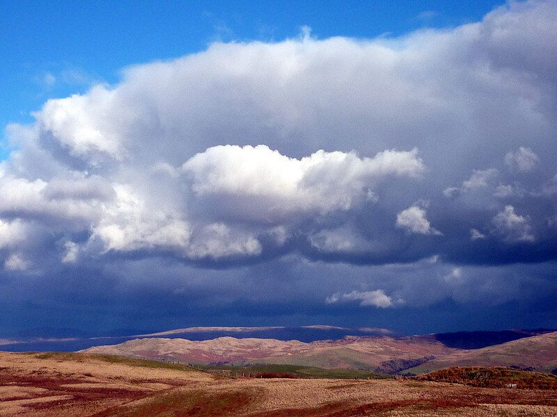 A landscape with rolling hills and a cloudy sky.