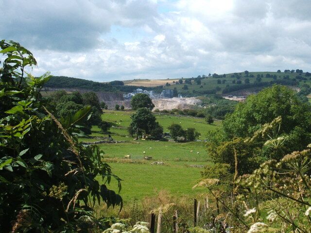 A rural landscape with rolling hills, green fields, and scattered trees.