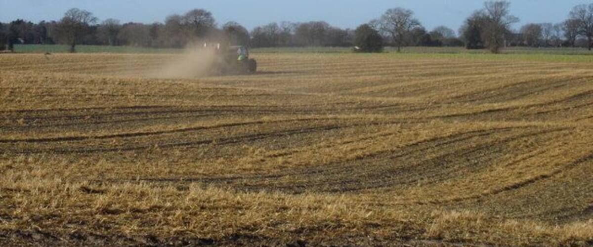 A tractor plowing a field with a clear sky.