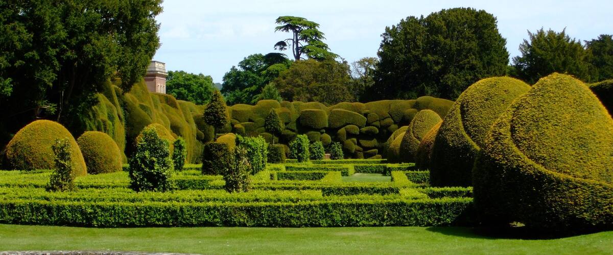 A meticulously landscaped garden with topiary sculptures, a pond, and a variety of trees.