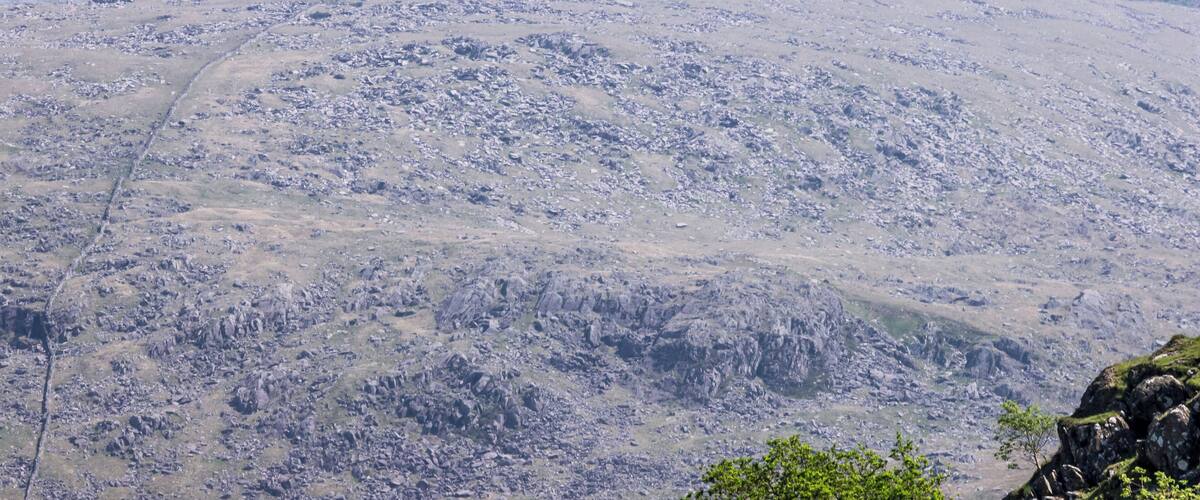 A rugged mountain landscape with rocky terrain and sparse vegetation.