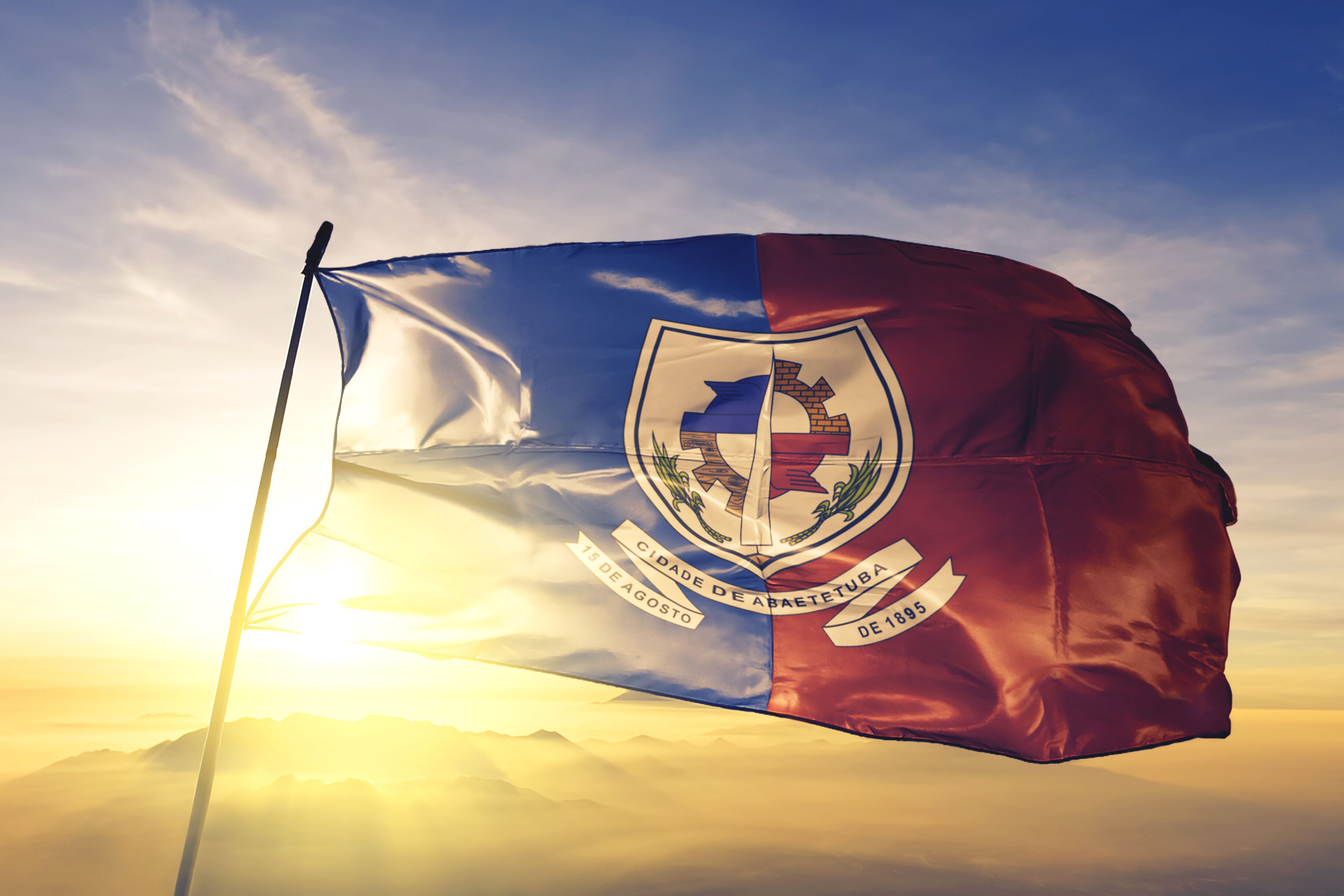 A flag with a coat of arms, the date '15 de agosto de 1895', and the text 'CIDADE DE ABAETTIBA'.