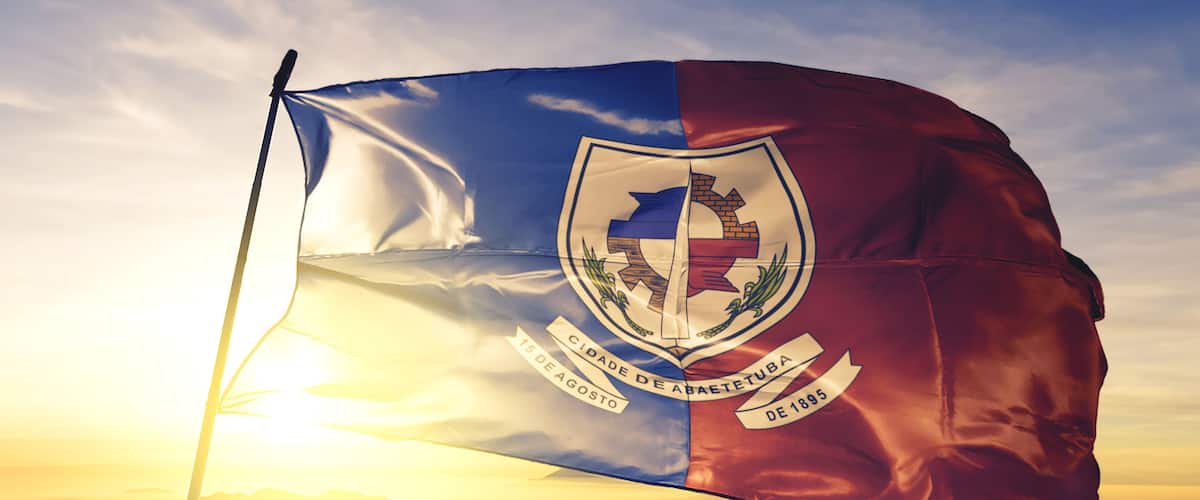 A flag with a coat of arms, the date '15 de agosto de 1895', and the text 'CIDADE DE ABAETTIBA'.