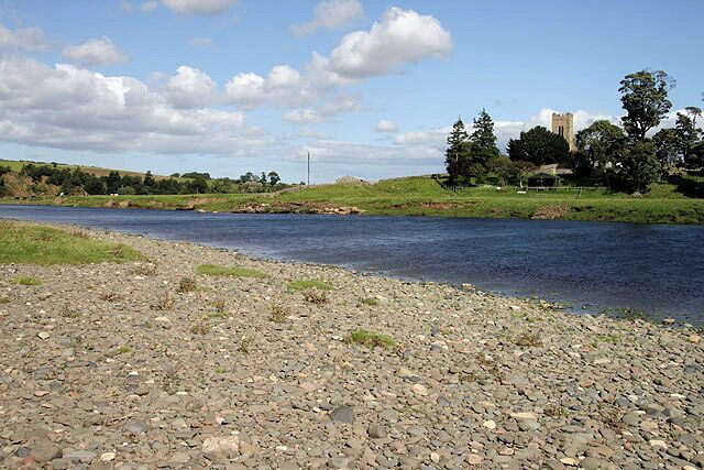 The River Tweed Viewed from the west bank at Birgham Haugh in Scotland with Carham Church tower to the right on the opposite side in England.