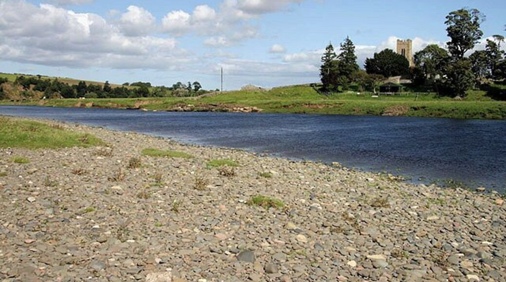 The River Tweed Viewed from the west bank at Birgham Haugh in Scotland with Carham Church tower to the right on the opposite side in England.