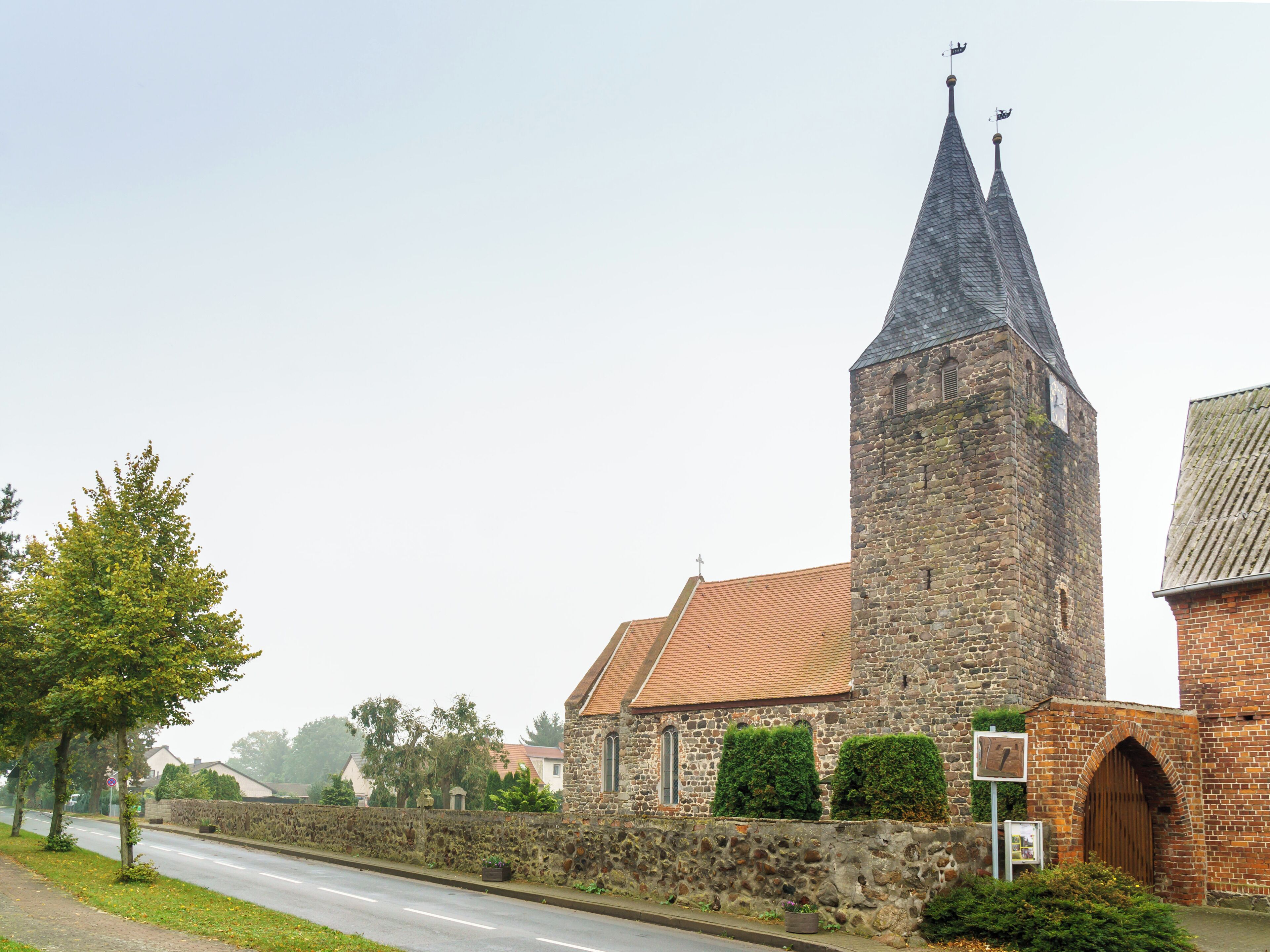 Kirche Klein Schwechten mit einem in der Friedhofsmauer teilweise eingemauerten Gotisches Kreuz