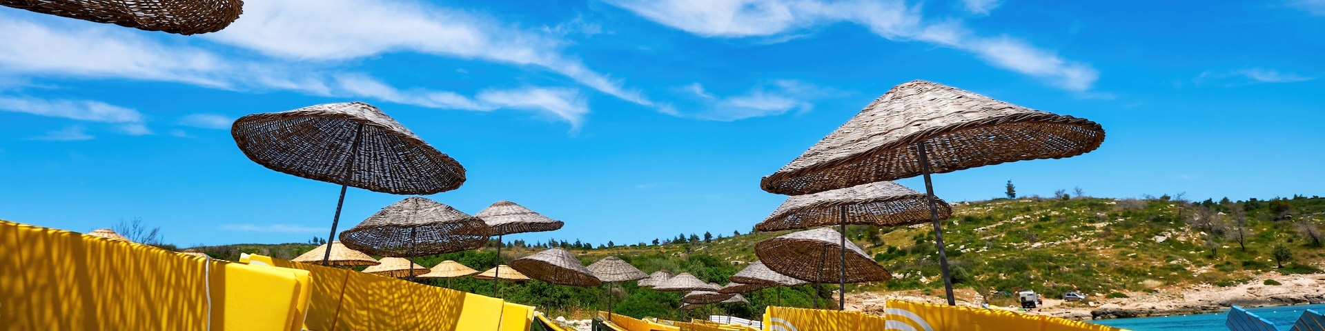 Uma praia de pedras com guarda-sóis e espreguiçadeiras.