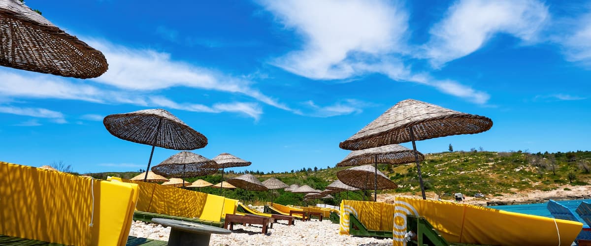 A pebble beach with umbrellas and lounge chairs.