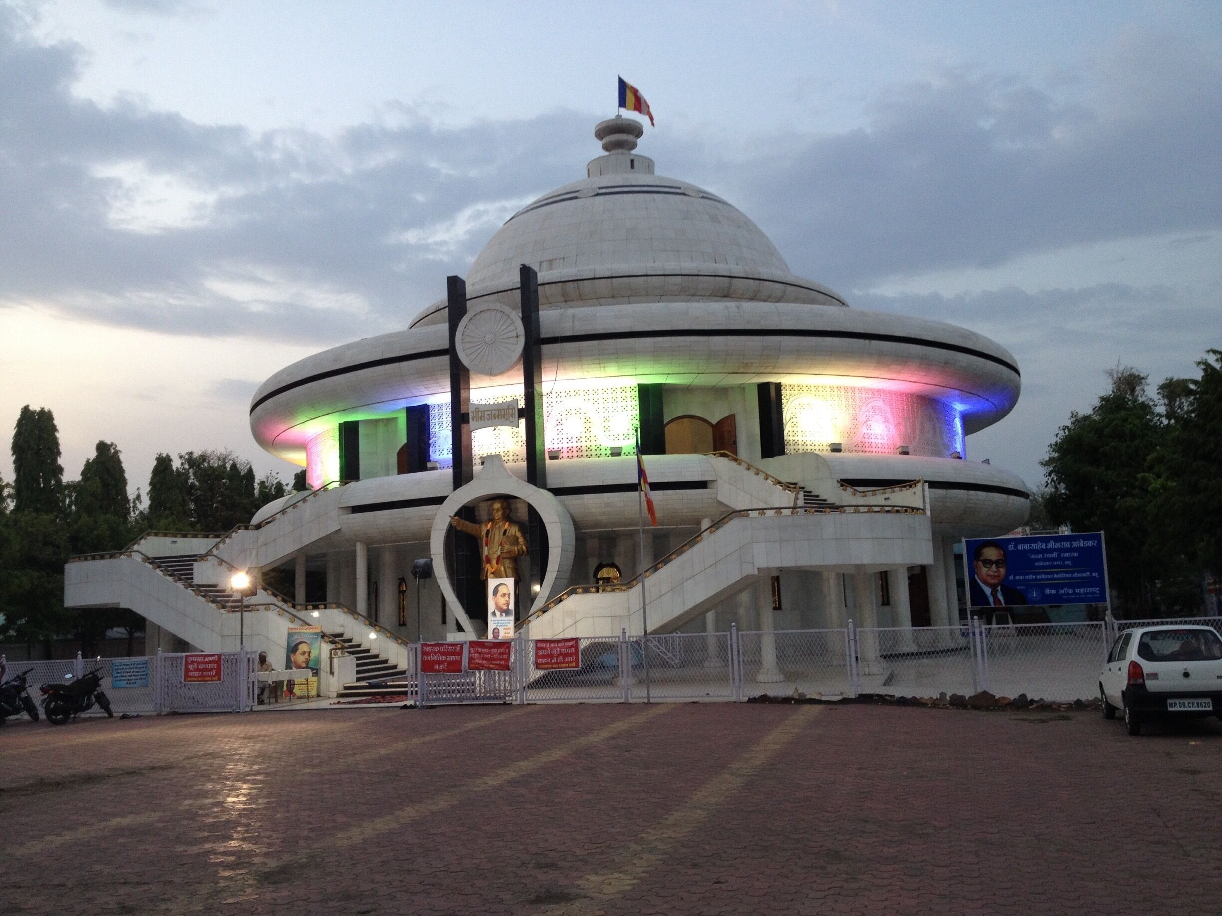 A large, dome-shaped building with a flag on top, surrounded by a fence and a statue in front.