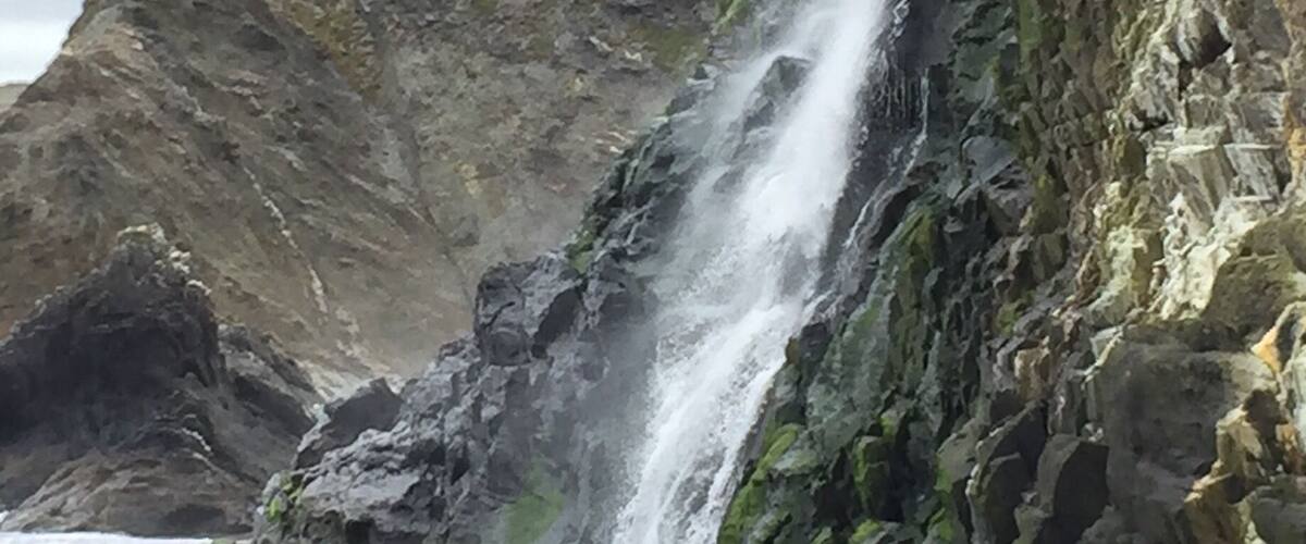 A waterfall cascading down a rocky cliff into the ocean.