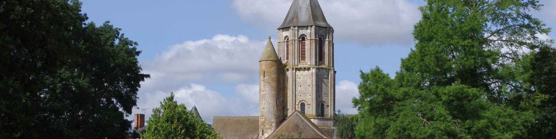 Trees and bell-tower of church Saint-Nicolas de Civray, France.