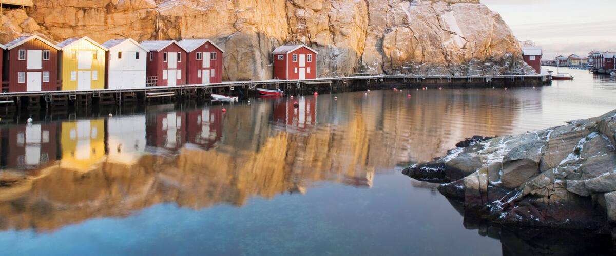 A coastal village with colorful wooden houses and a rocky cliff.
