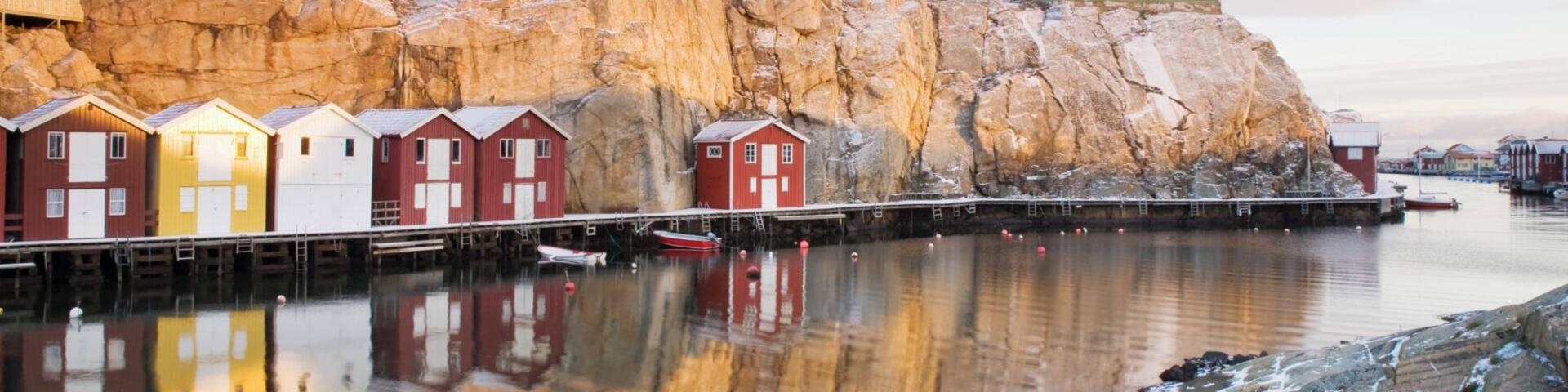 A coastal village with colorful wooden houses and a rocky cliff.