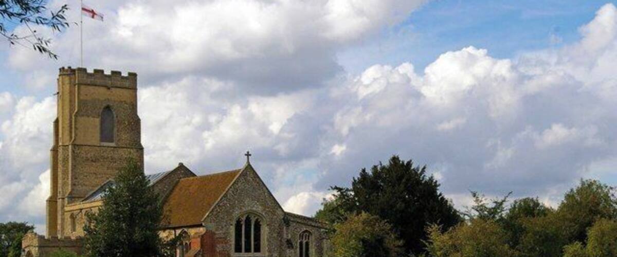 A church with a bell tower and a large field in the foreground.