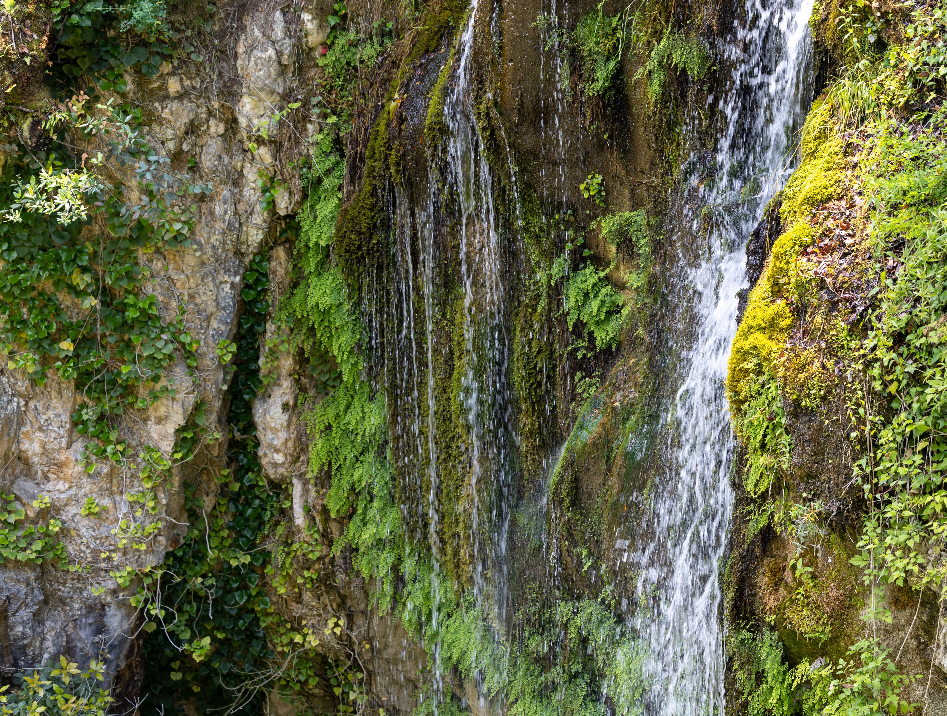 A waterfall cascading down a moss-covered rock face.