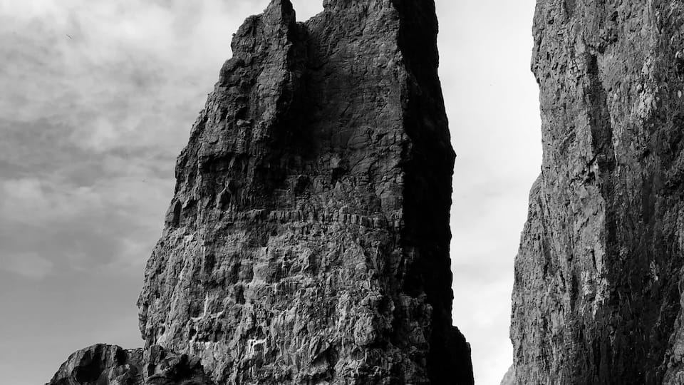 A rugged coastal landscape with towering rock formations and a calm sea.