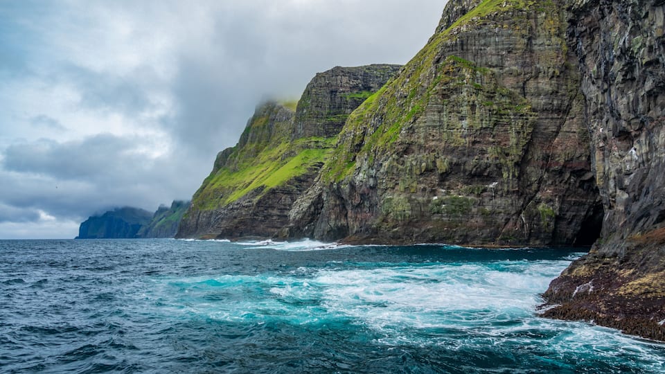 A rugged coastline with steep cliffs and turbulent sea waves.