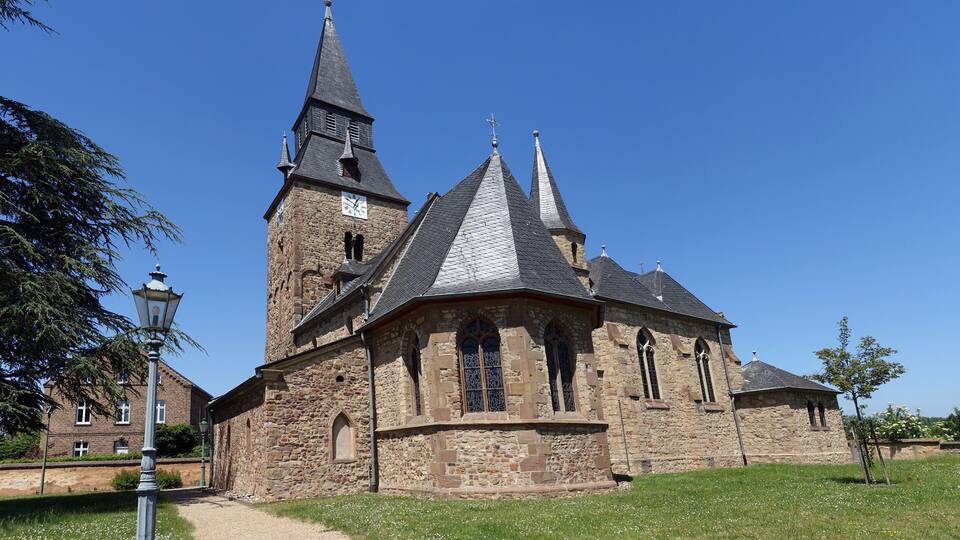 A historic church with a tall steeple and multiple pointed roofs.