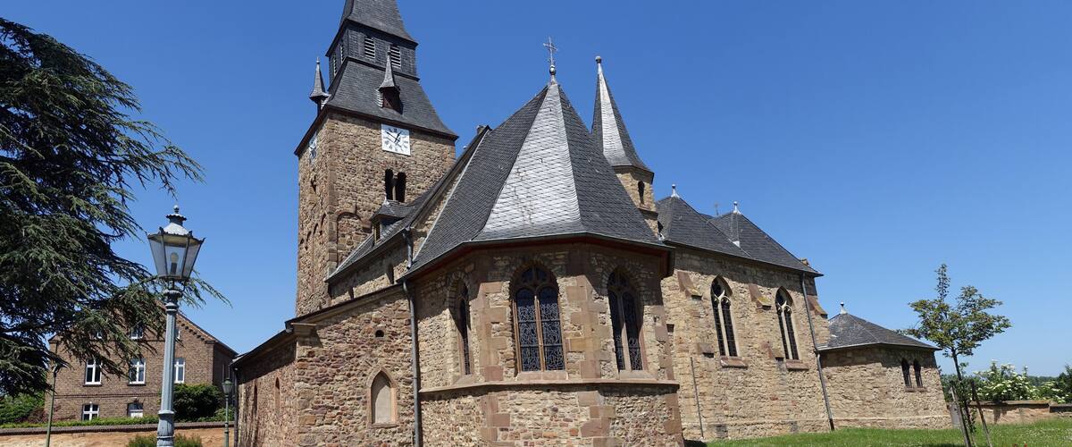 A historic church with a tall steeple and multiple pointed roofs.