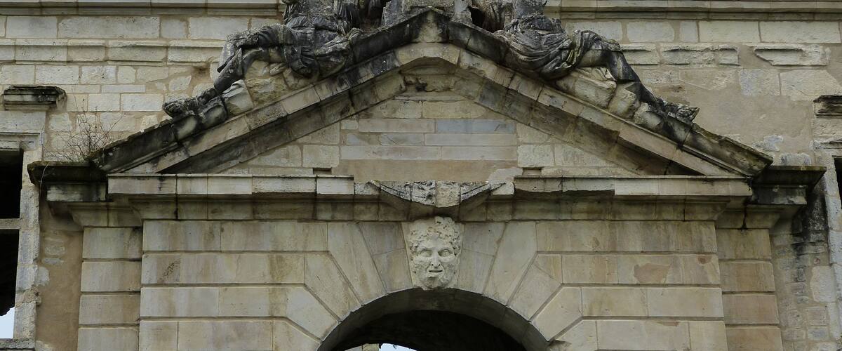 An arched stone gateway with intricate carvings and a lion statue on top.