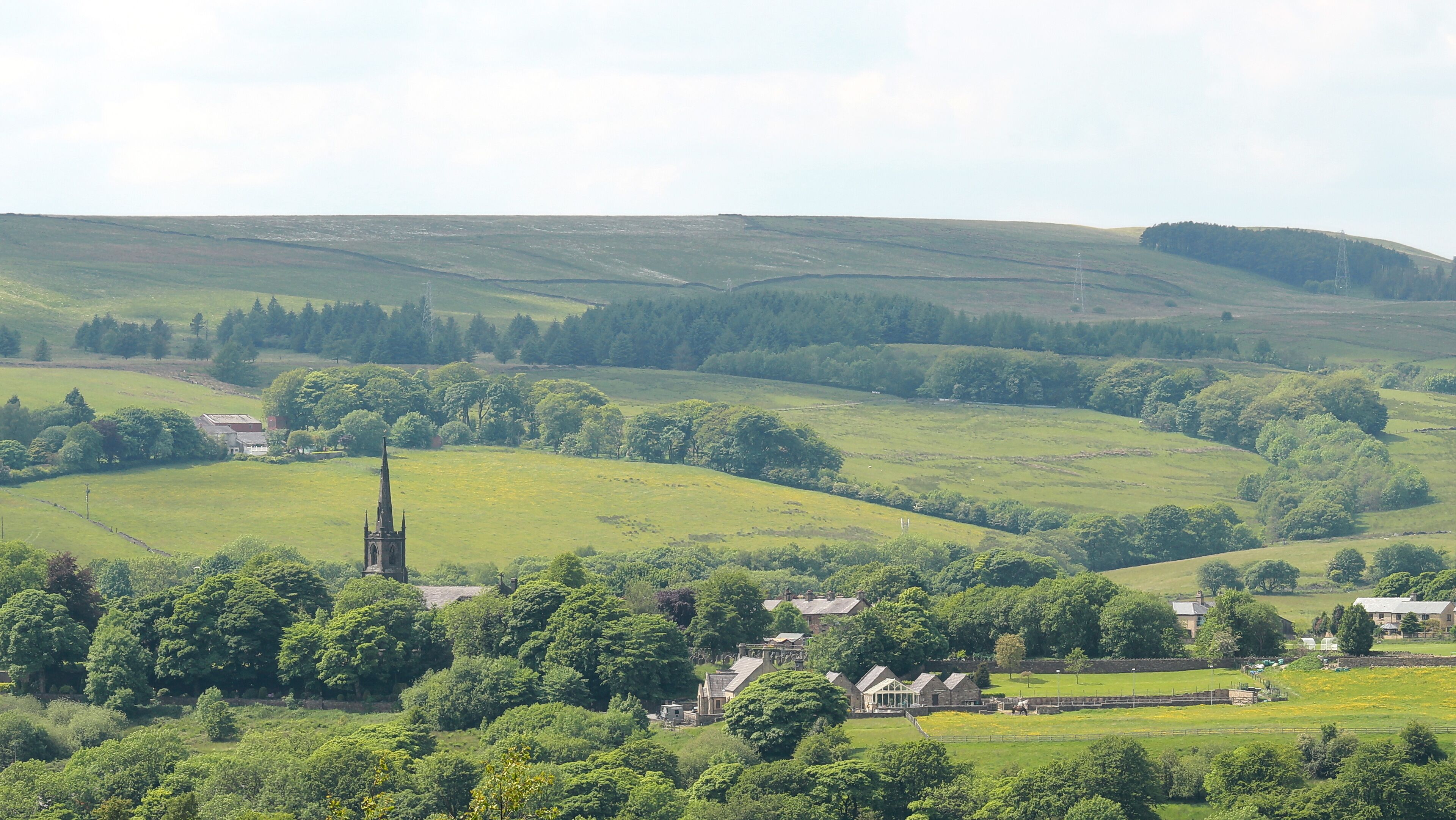 A rural landscape with rolling hills, a church, and scattered houses.