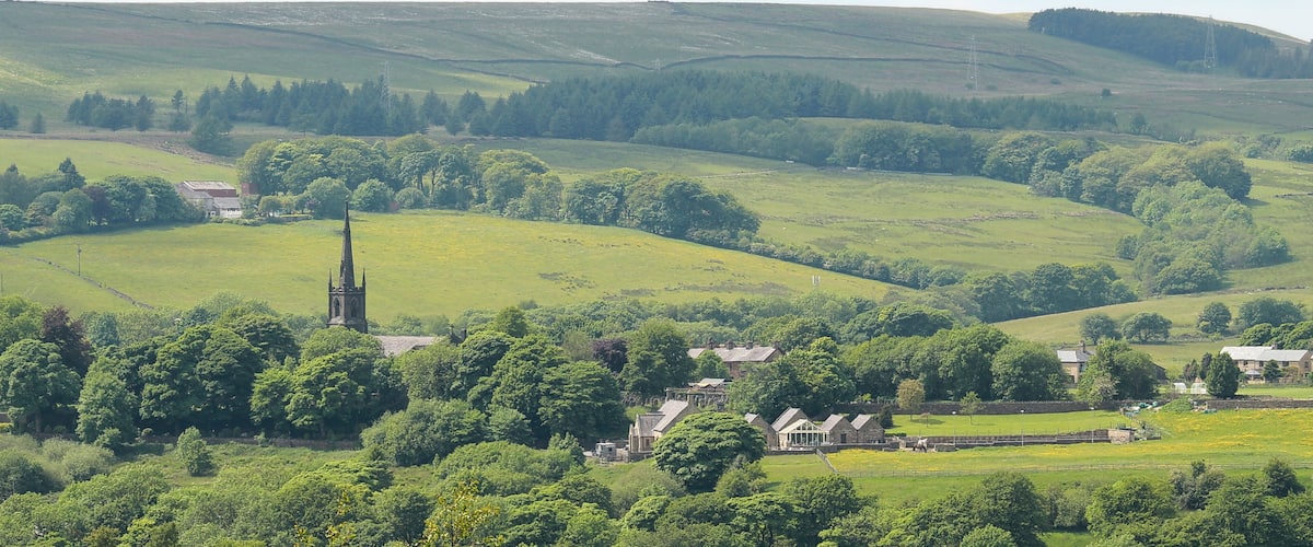 A rural landscape with rolling hills, a church, and scattered houses.