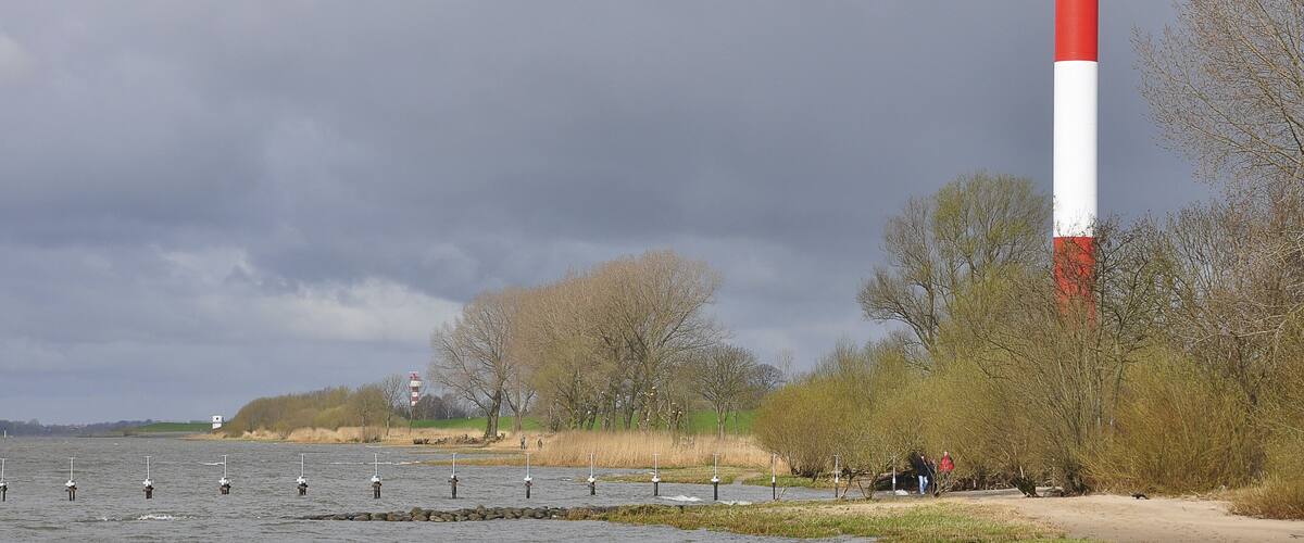 A lighthouse by a body of water with overcast skies.