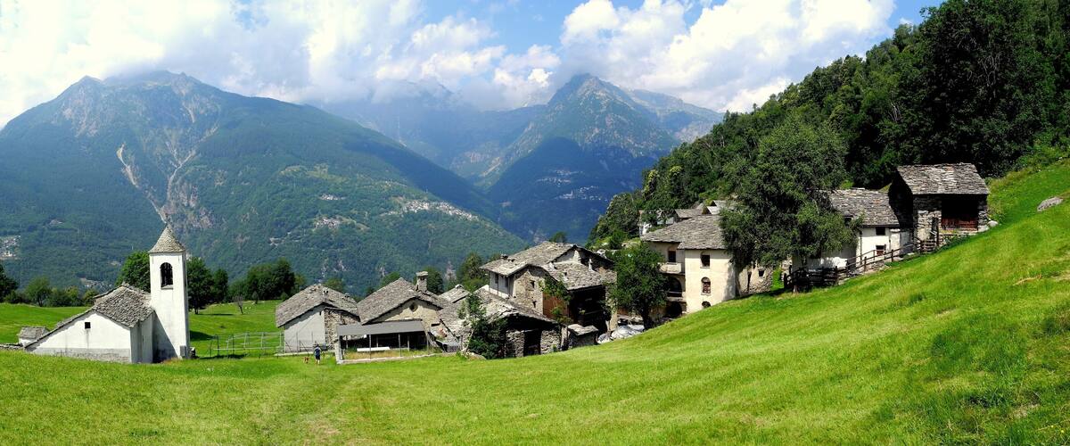 A village nestled in a valley with mountains in the background.