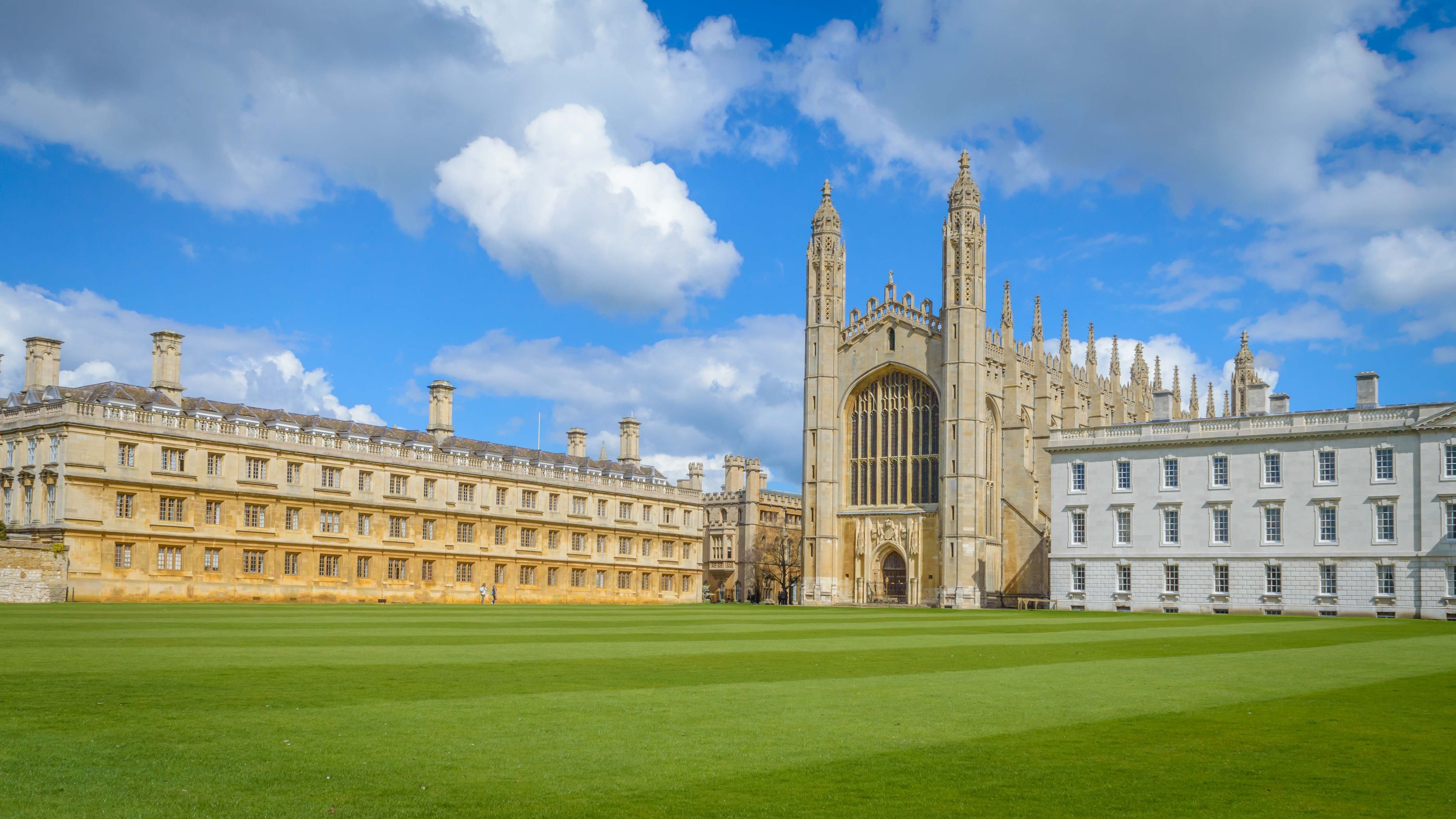 A historic university campus with a prominent Gothic-style building and a well-maintained lawn.