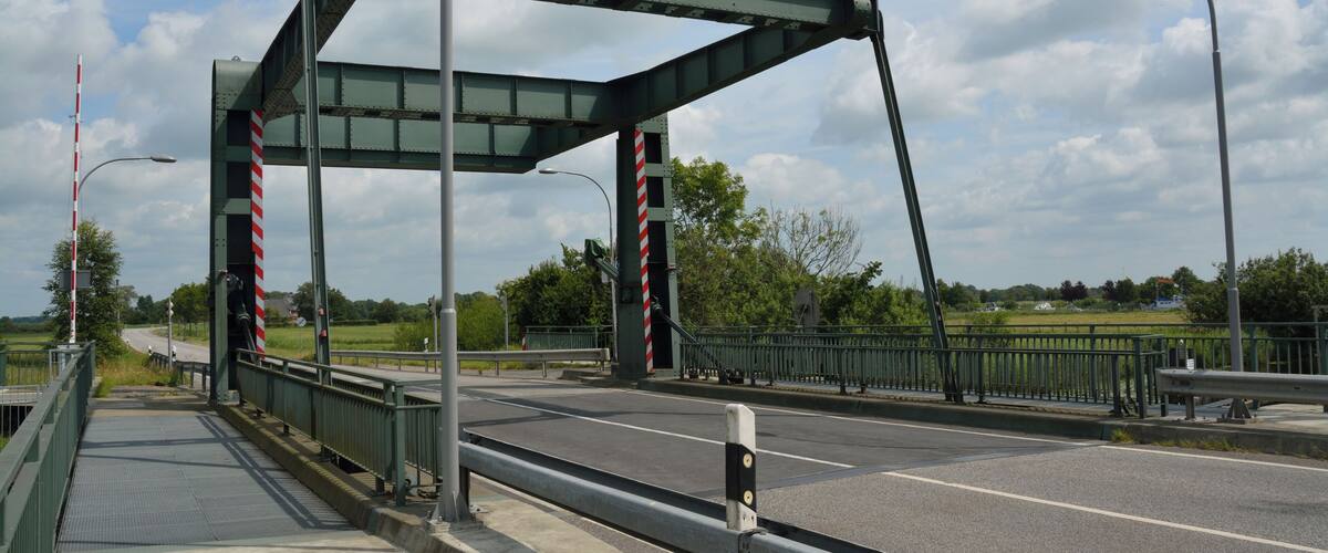 A pedestrian bridge with metal railings and a glass walkway over a road.