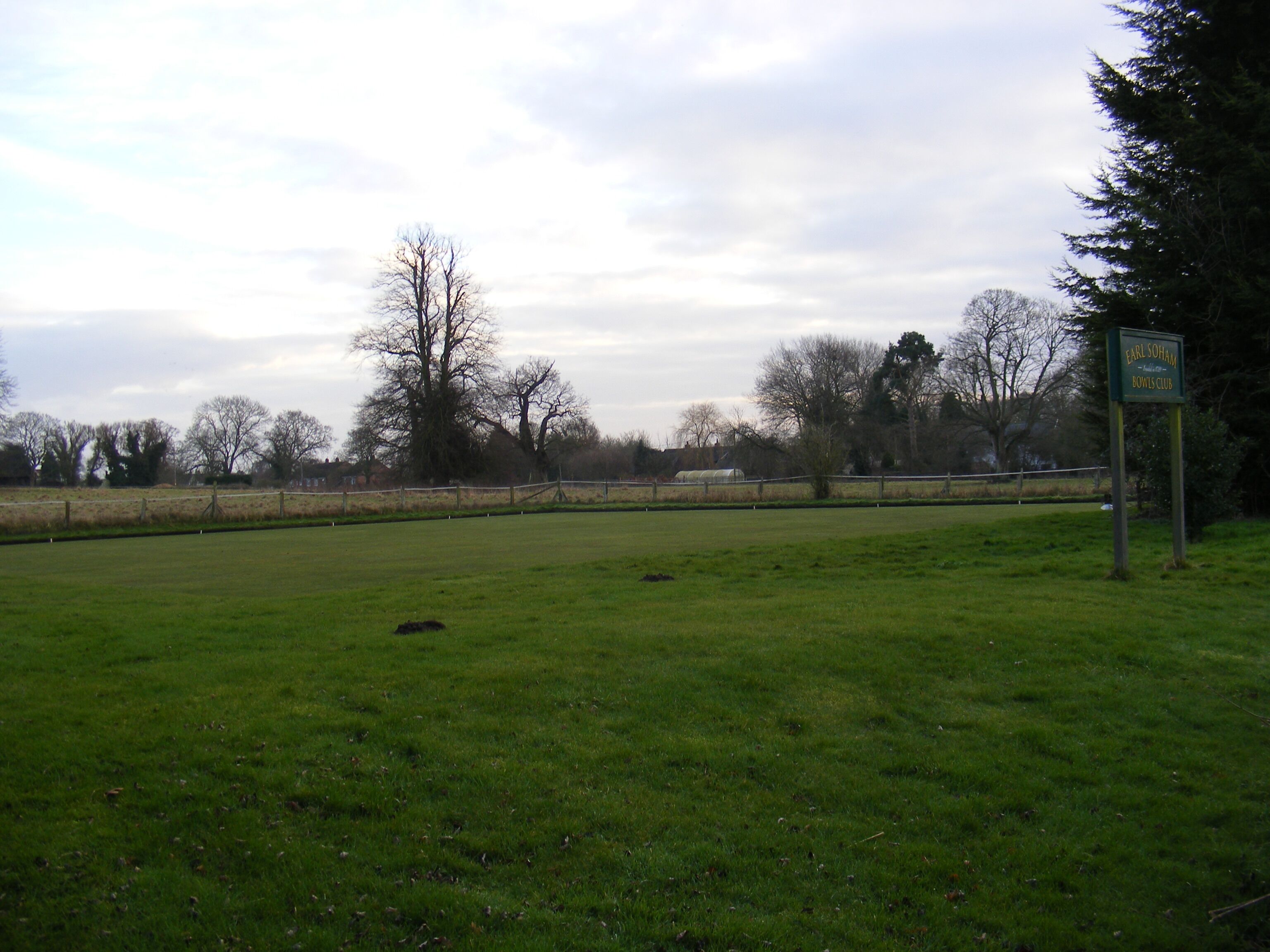 A grassy field with a sign for Earl Soham Rowles Club.
