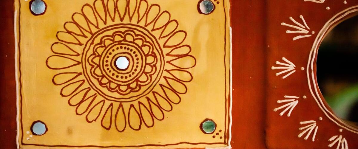 A decorative tile with a central circular pattern surrounded by four smaller circles, set against a reddish-brown background.