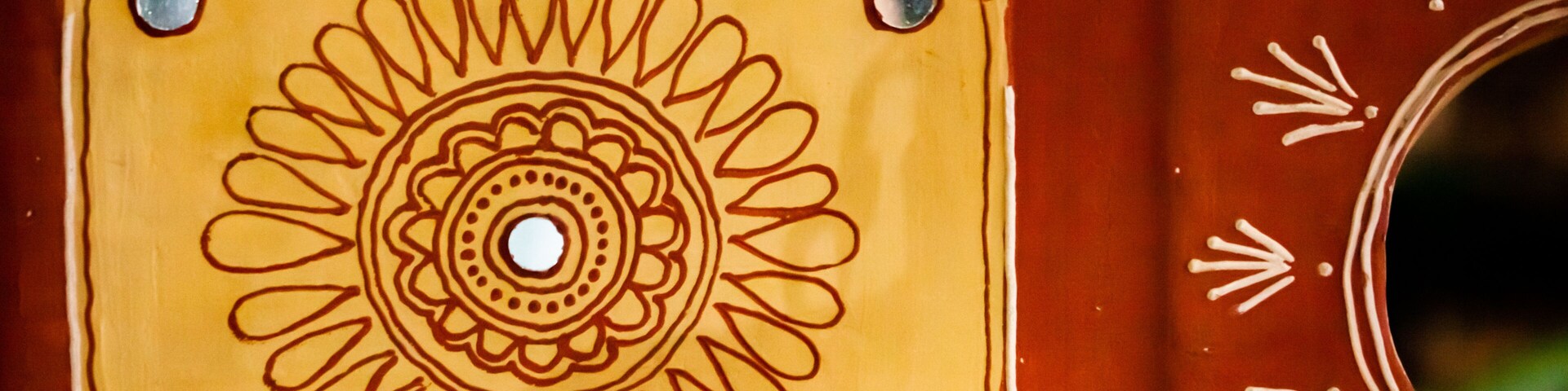 A decorative tile with a central circular pattern surrounded by four smaller circles, set against a reddish-brown background.