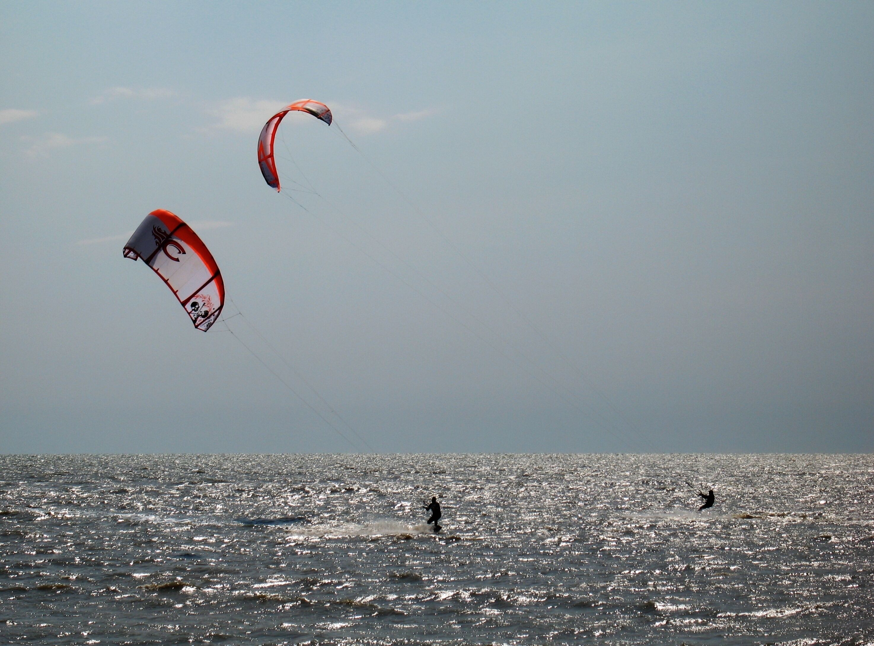 A person kite surfing in the ocean with a clear sky.