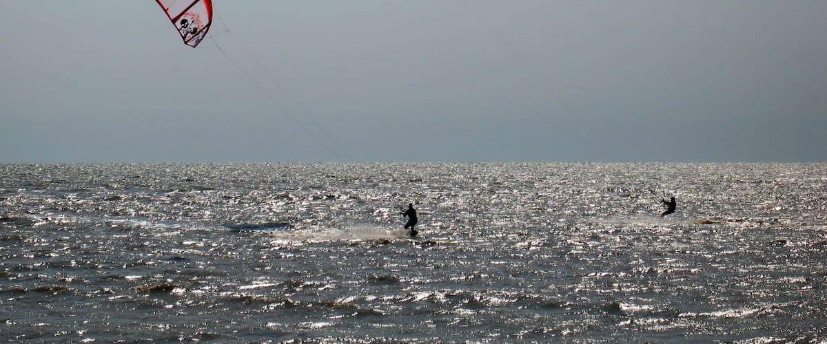 A person kite surfing in the ocean with a clear sky.
